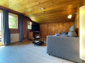 Interior acogedor de una cabaña con un sofá, un televisor y una mesa de comedor.