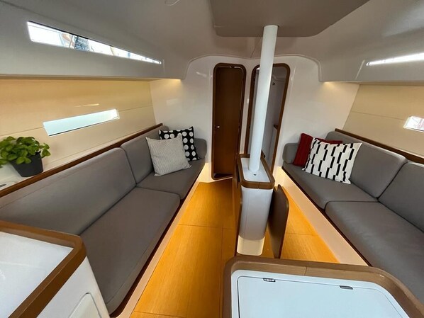 Ein modernes Interieur mit einer zentralen Gäng, gepolsterten Sitzen rechts und links, einem kleinen Tisch und einem Topf mit Pflanze.