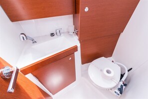 Et lille badeværelse med en hvid vask, toilet og et træskab.