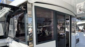 Un camping-car blanc doté de grandes fenêtres, d’une porte coulissante et d’un intérieur visible, avec un lit et un espace de rangement.