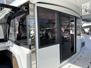 Ein weißer Wohnmobil mit großen Fenstern, einer Schiebetür und einem sichtbaren Innenraum mit Bett und Stauraum.