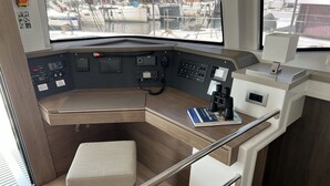 Un poste de pilotage de bateau, doté d’un siège rembourré, de panneaux de commande et d’un livre posé sur la table.