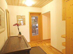 Ein Holzboden, eine Tür mit Milchglas, ein gerahmtes Bild und eine Vase mit Blumen.
