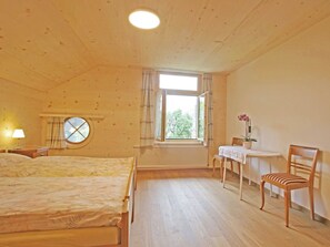 A room with two beds, a small table with a chair, a radiator, and a window with curtains. - Pfander Appartement/Fewo, Dusche und Bad, WC, 3 Schlafräume 7-Bettwohnung by Interhome (Zweisimmen)