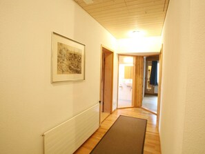 Ein Flur mit Heizkörper, einem gerahmten Bild und einer Tür zum Badezimmer.