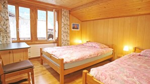 A wooden cabin bedroom with two beds, a desk, and a chair. - Pfander Appartement/Fewo, Dusche und Bad, WC, 3 Schlafräume 7-Bettwohnung by Interhome (Zweisimmen)