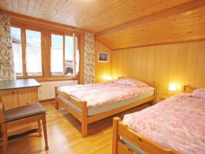 Ein Schlafzimmer einer Holzhütte mit zwei Betten, einem Schreibtisch und einem Stuhl.
