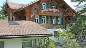 A multi-story wooden chalet with a sloped roof, balconies with flower boxes, and large windows. - Pfander Appartement/Fewo, Dusche und Bad, WC, 3 Schlafräume 7-Bettwohnung by Interhome (Zweisimmen)