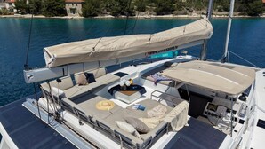 A yacht with a covered deck area featuring seating, a small table with flowers, and a flag. - Sun-kissed Sailing Adventure in Split-Dalmatia, Croatia (Seget Donji)