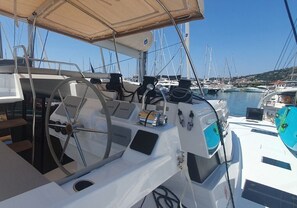 Posto de comando de um veleiro, com leme, equipamentos de navegação Garmin e toldo.