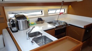 Een kleine keuken met een spoelbak, fornuis en een klein raam.