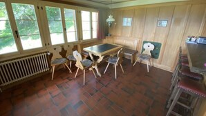 A room with a table and chairs, a radiator, and a window with a view of trees. - Sonnige Matte Appartement/Fewo, Dusche oder Bad, WC 8-Bettwohnung by Interhome (Gstaad)