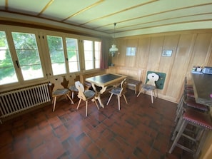 A room with a table and chairs, a radiator, and a window with a view of trees. - Sonnige Matte Appartement/Fewo, Dusche oder Bad, WC 8-Bettwohnung by Interhome (Gstaad)