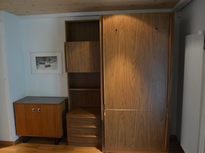 A room with a wooden wardrobe, a small desk, and a framed picture on the wall. - Oberland Nr. 19 Appartement/Fewo, Dusche oder Bad, WC 6-Bettwohnung by Interhome (Gstaad)