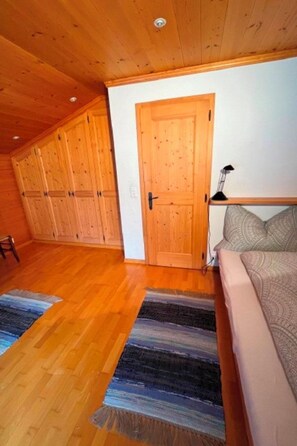 A room with wooden flooring, a sofa, a patterned rug, and a door. - Oberland Nr. 19 Appartement/Fewo, Dusche oder Bad, WC 6-Bettwohnung by Interhome (Gstaad)
