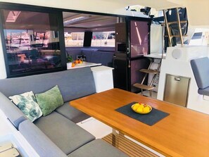 A compact interior with a sofa, dining table, and a view through a large window. - Sun-kissed Sailing Adventure in Split-Dalmatia, Croatia (Seget Donji)