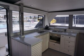 A modern kitchen with a large window, a built-in oven, and a sink. - Sun-Kissed Sailing Adventure in Islas Sarónicas (Alimos)