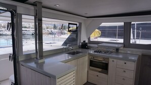 A modern kitchen with a large window, a built-in oven, and a sink. - Sun-Kissed Sailing Adventure in Islas Sarónicas (Alimos)
