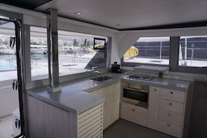 A modern kitchen with a large window, a built-in oven, and a sink. - Sun-Kissed Sailing Adventure in Islas Sarónicas (Alimos)