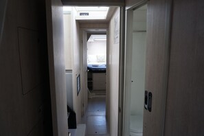A narrow hallway leading to a bedroom with a bed and a window. - Sun-Kissed Sailing Adventure in Islas Sarónicas (Alimos)
