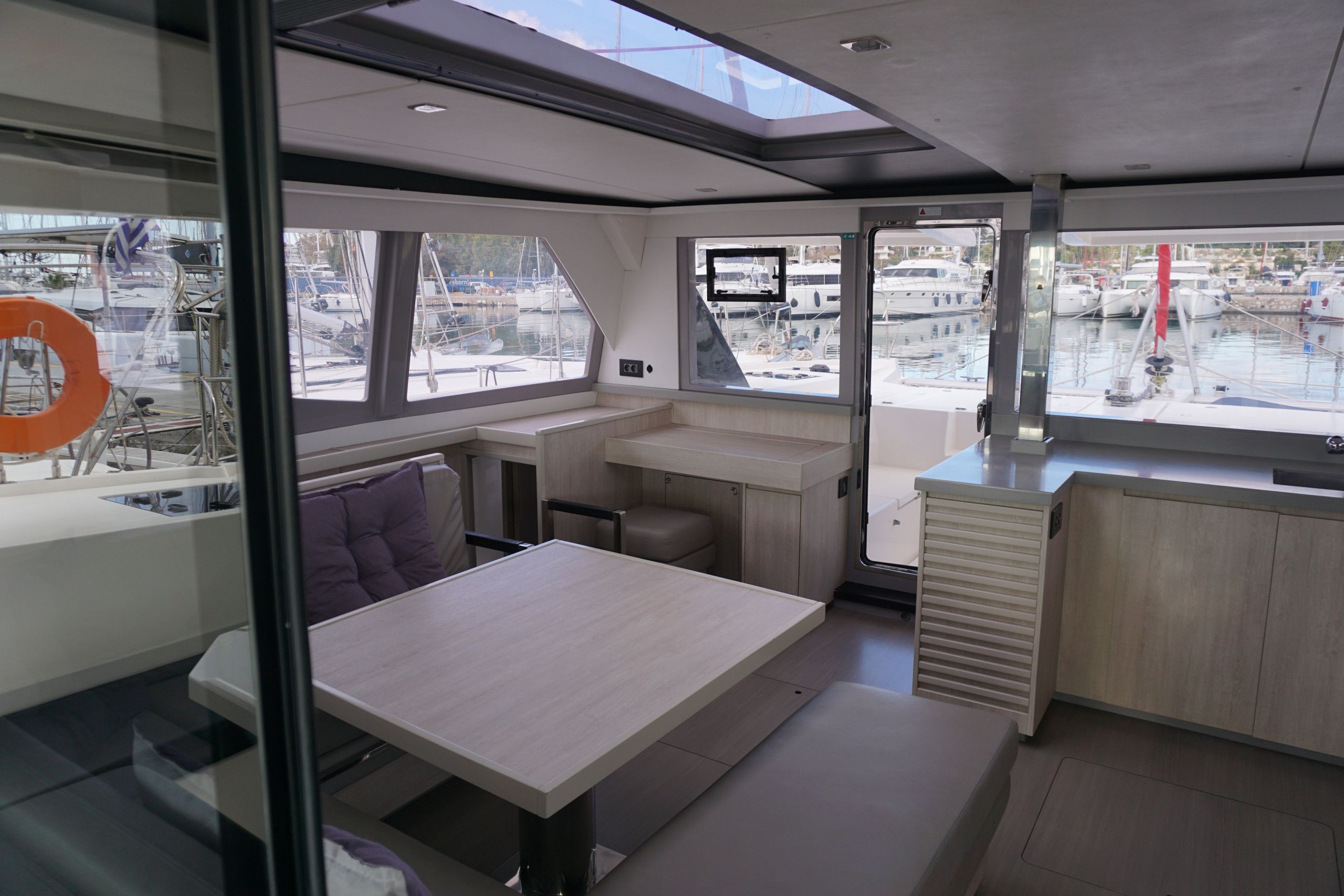 A modern interior with a dining area, a small kitchen, and a seating space with a view of the marina.