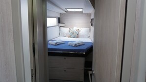 A compact bedroom with a bed, pillows, and a small window. - Sun-Kissed Sailing Adventure in Islas Sarónicas (Alimos)