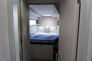 A compact bedroom with a bed, pillows, and a small window. - Sun-Kissed Sailing Adventure in Islas Sarónicas (Alimos)