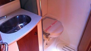 A compact bathroom with a sink, toilet, and shower. - Sun-Kissed Sailing Adventure in the Saronic Islands (Lavrio)