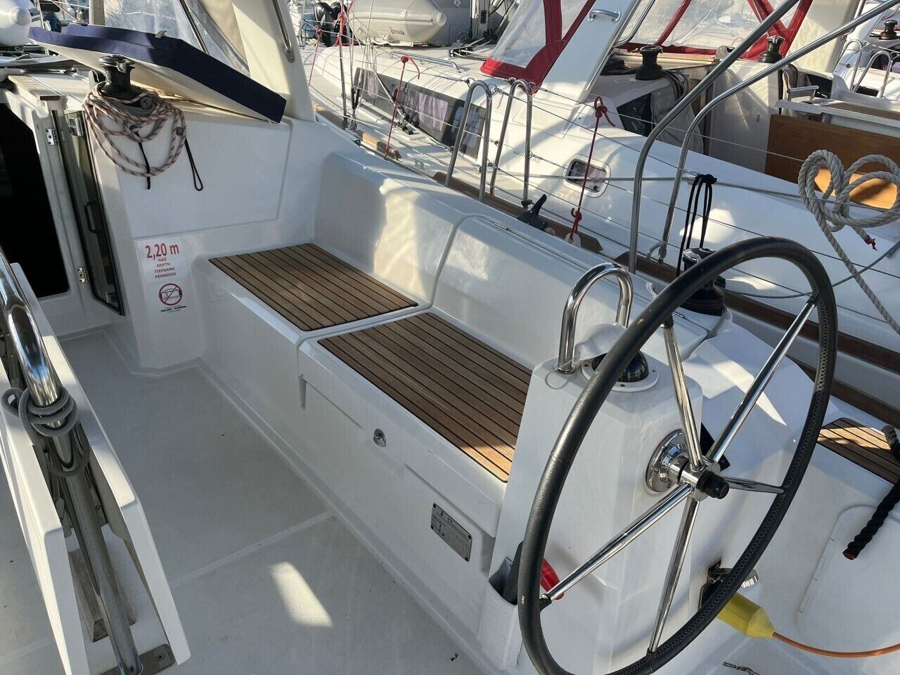 Das Deck eines Bootes mit Steuer, einer Holzbank und einer Tiefenmarkierung.