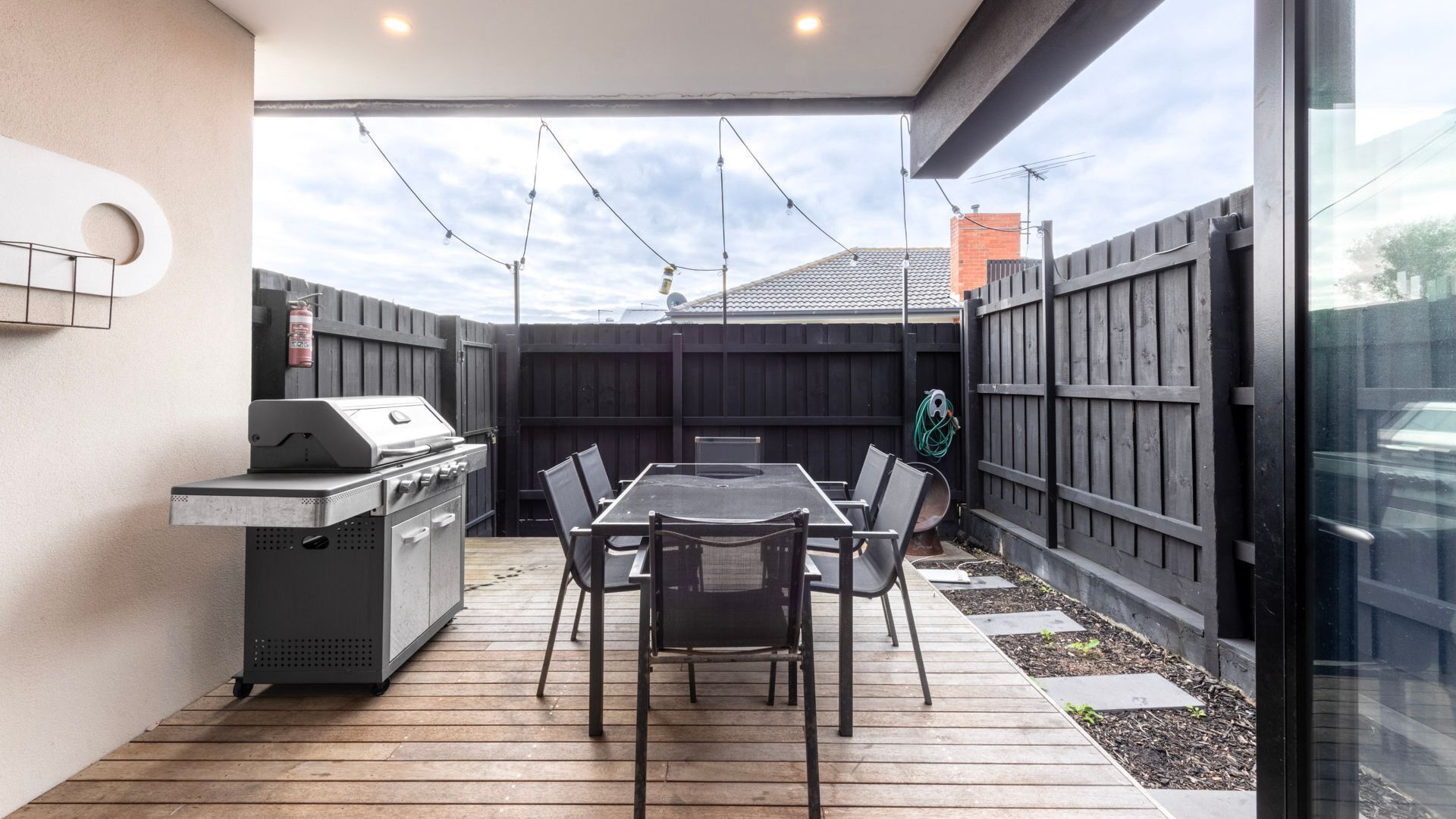 A patio with a grill, table, and chairs.