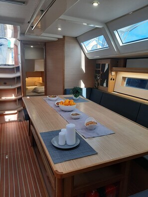 A compact, modern interior with a long dining table, a seating area with cushions, a small kitchenette, and a skylight. - Sun-kissed Sailing Adventure in Split-Dalmatia, Croatia (Trogir)
