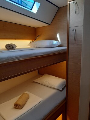 Ein Schlafraum mit Etagenbetten, einem Dachfenster, Holzwänden und einem Kleiderschrank.
