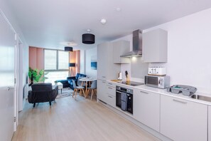 A modern kitchen with white cabinets, a built-in oven, a microwave, and a toaster. - 1BDR Open Plan Apartment With Full Kitchen (Stretford)