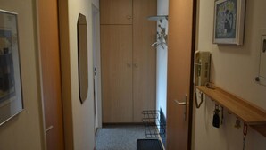 A narrow hallway with a wooden door, a coat rack, and a shelf with keys. - Mösli (Zimmerli) Appartement/Fewo, Dusche oder Bad, WC 2-Bettwohnung by Interhome (Zweisimmen)