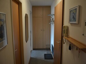 A narrow hallway with a wooden door, a coat rack, and a shelf with keys. - Mösli (Zimmerli) Appartement/Fewo, Dusche oder Bad, WC 2-Bettwohnung by Interhome (Zweisimmen)