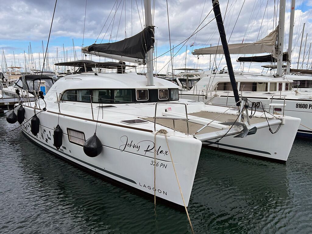 Un yacht blanc, baptisé « Johnny Relax », était amarré dans une marina, aux côtés d’autres bateaux.