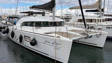 Un yacht blanc, baptisé « Johnny Relax », était amarré dans une marina, aux côtés d’autres bateaux.