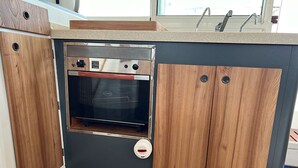 A compact kitchen with a built-in oven, wooden cabinets, and a countertop. - Sun-Kissed Sailing Adventure in Northern Croatia (Punat)