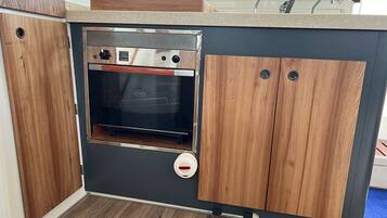 Une cuisine de taille réduite, dotée d’un four encastré, de meubles en bois et d’un plan de travail.