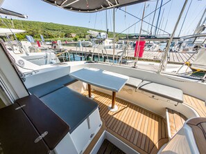 A boat deck with a table and seating, surrounded by water and other boats. - Sun-Kissed Sailing Adventure in Northern Croatia (Punat)