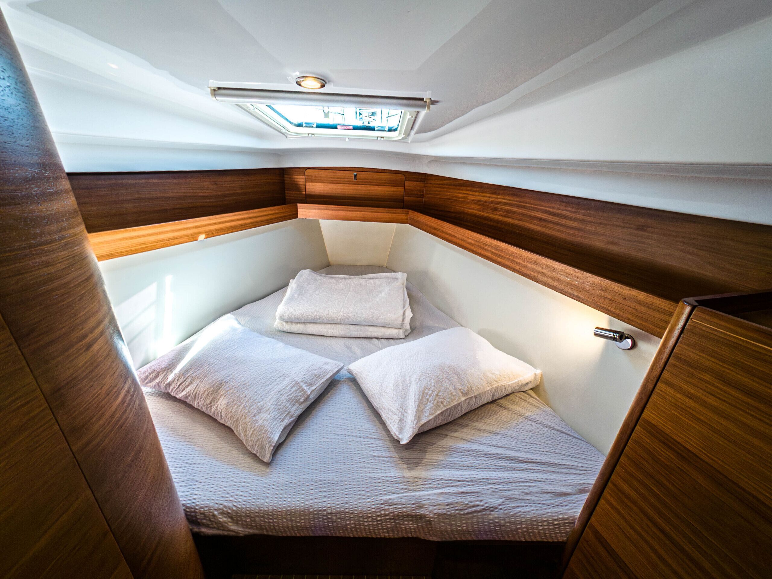 Una cabaña pequeña y luminosa, con cama, un ventanal y paneles de madera.