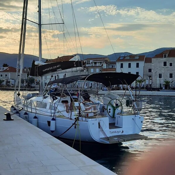 A sailboat docked at a marina with a view of buildings and hills in the background. - Sun-Kissed Sailing Adventure in Northern Croatia (Punat)