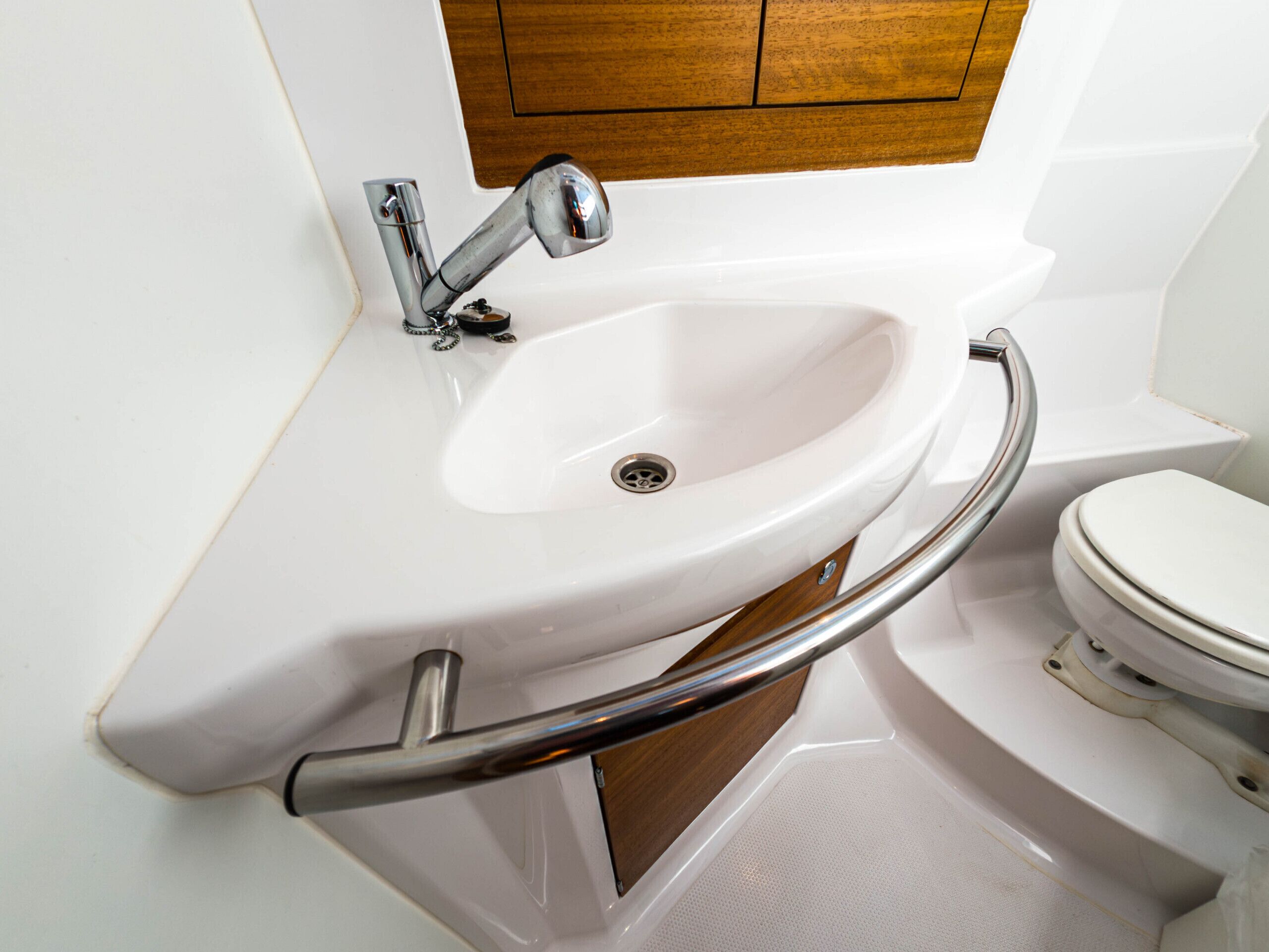 A bathroom with a white sink, chrome faucet, and a wooden cabinet above.