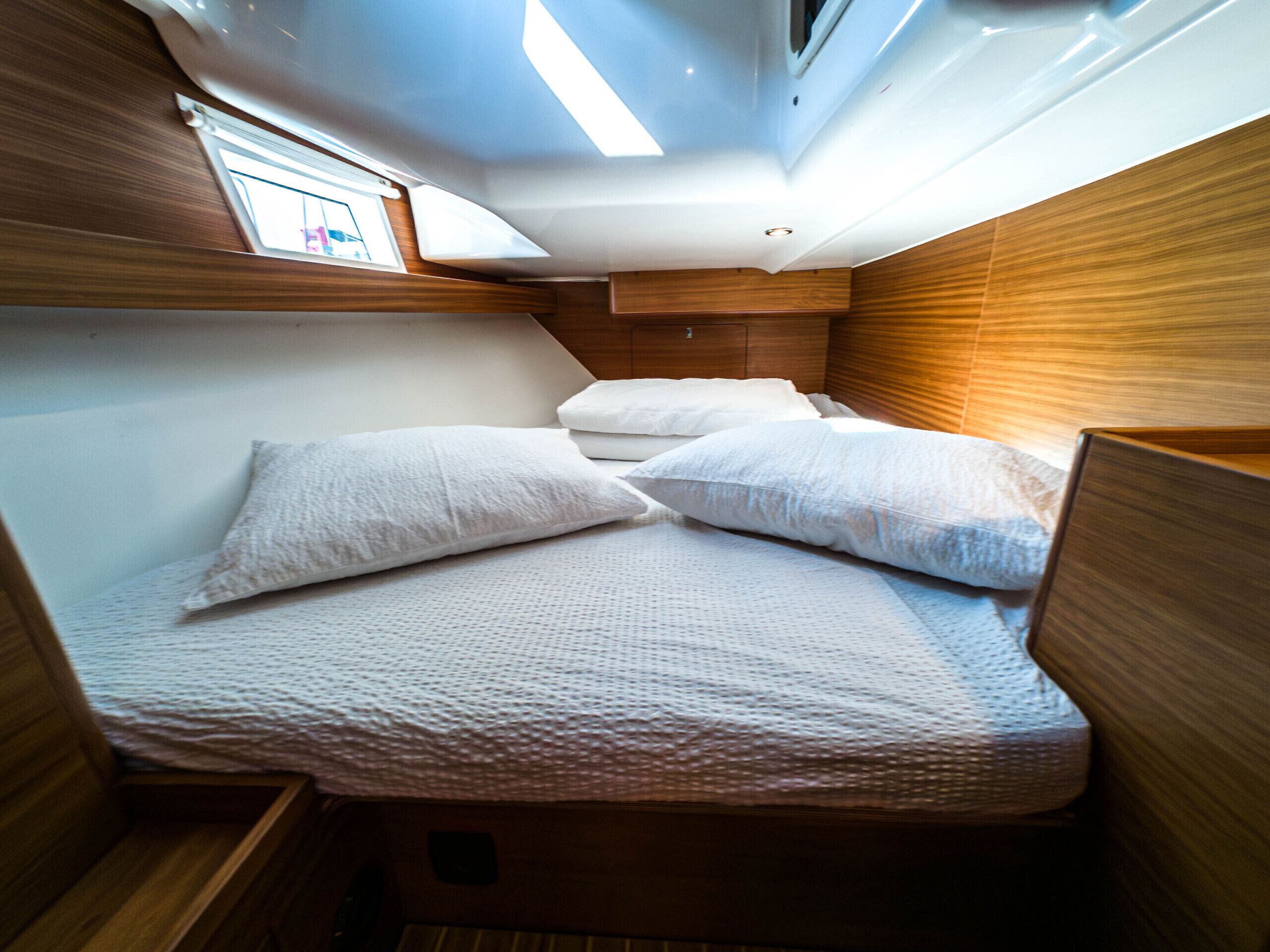 A compact cabin with a bunk bed, wooden walls, and a skylight.