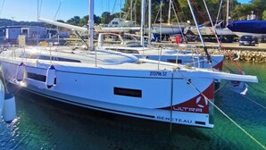 Un voilier portant le nom de « BENETEAU » était amarré dans une marina, avec d’autres bateaux en arrière-plan.