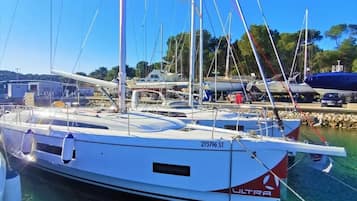 Eine Segelyacht vom Typ BENETEAU liegt in einer Marina, im Hintergrund weitere Boote.