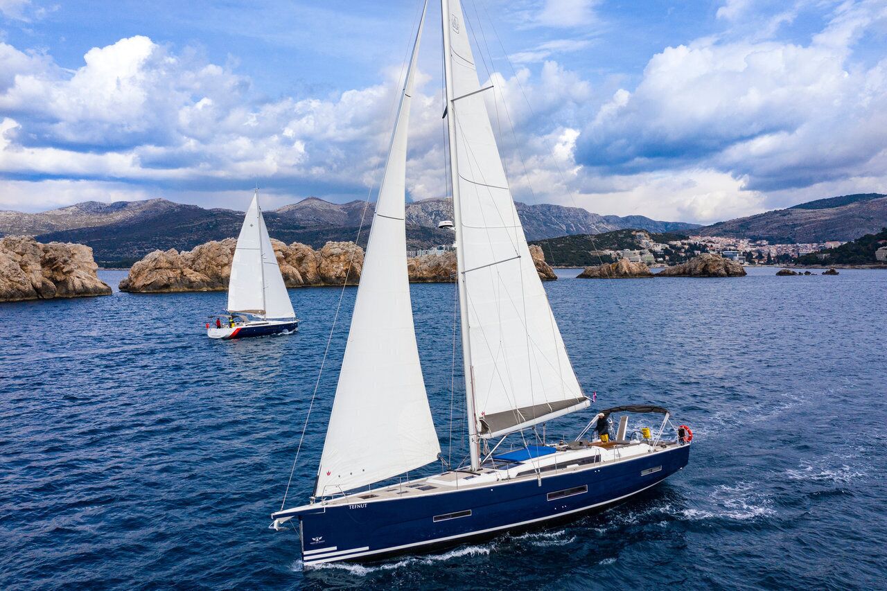 A sailboat on calm waters with a mountainous backdrop.