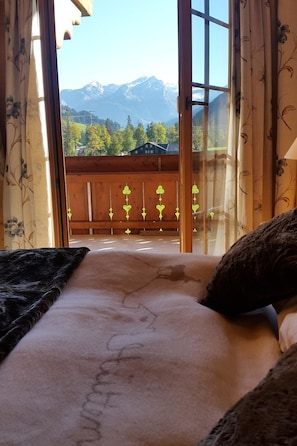 Una habitación con una cama, vistas a la montaña y un balcón con barandilla.