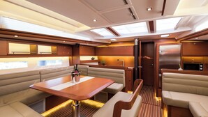 Interior de barco com área de jantar, assentos, cozinha e dispensa.