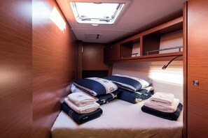 A compact, well-lit interior with a skylight, a bed with neatly folded towels, and wooden cabinetry. - Sun-Kissed Sailing Adventure in Sibenik, Croatia (Primošten)